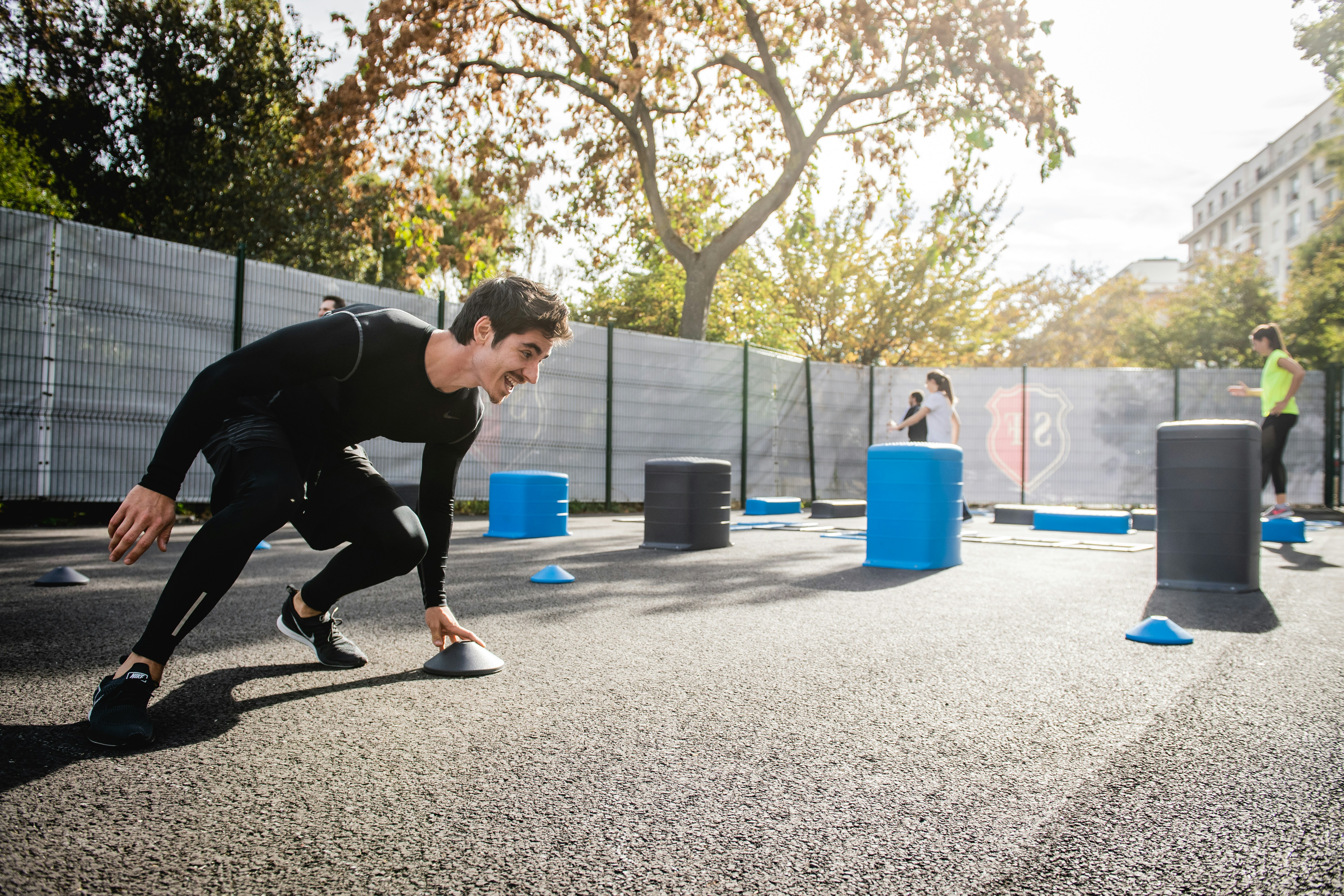 A man running agility drills with barrels and cones.