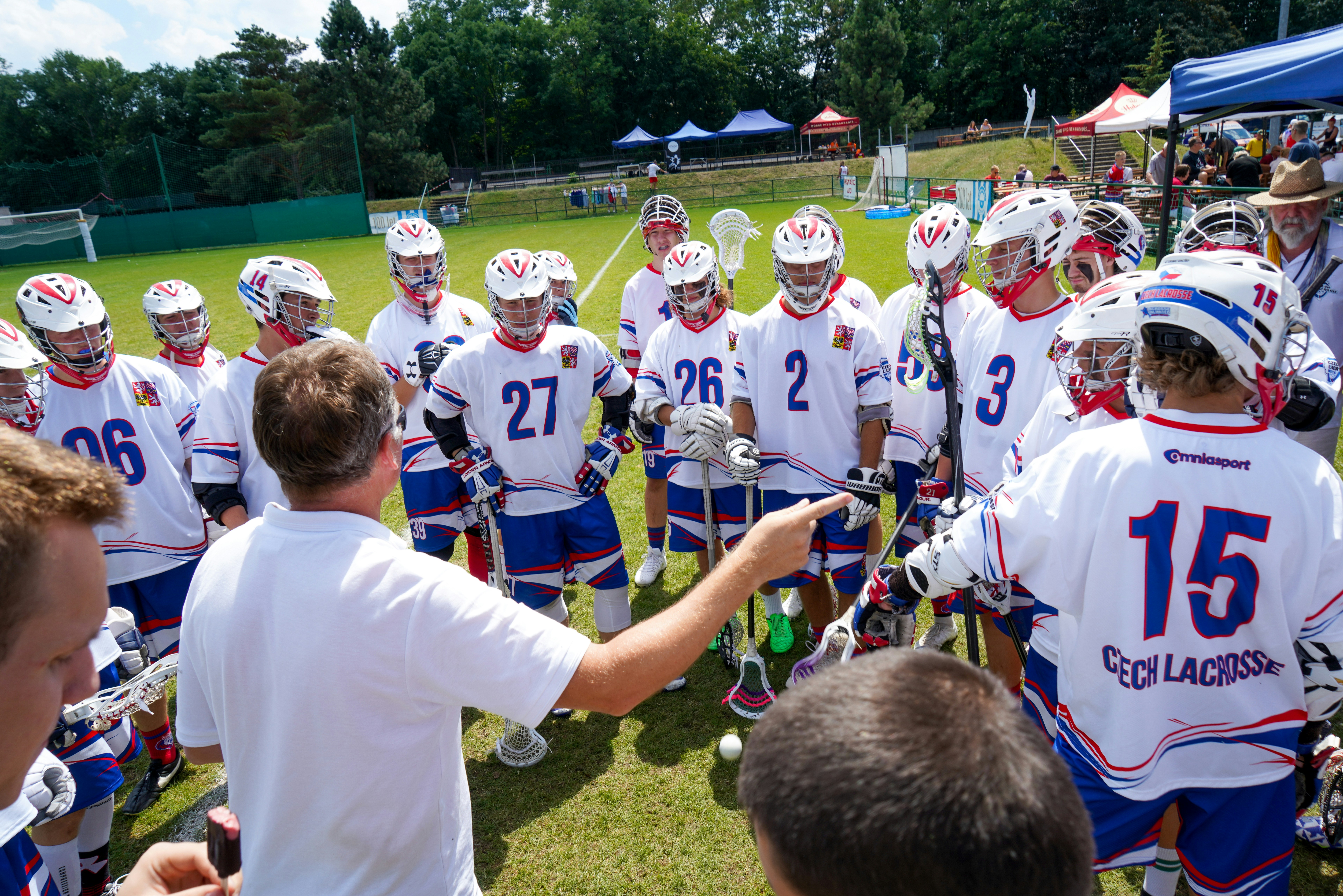 A lacrosse coach teaching a group of men's lacrosse players.