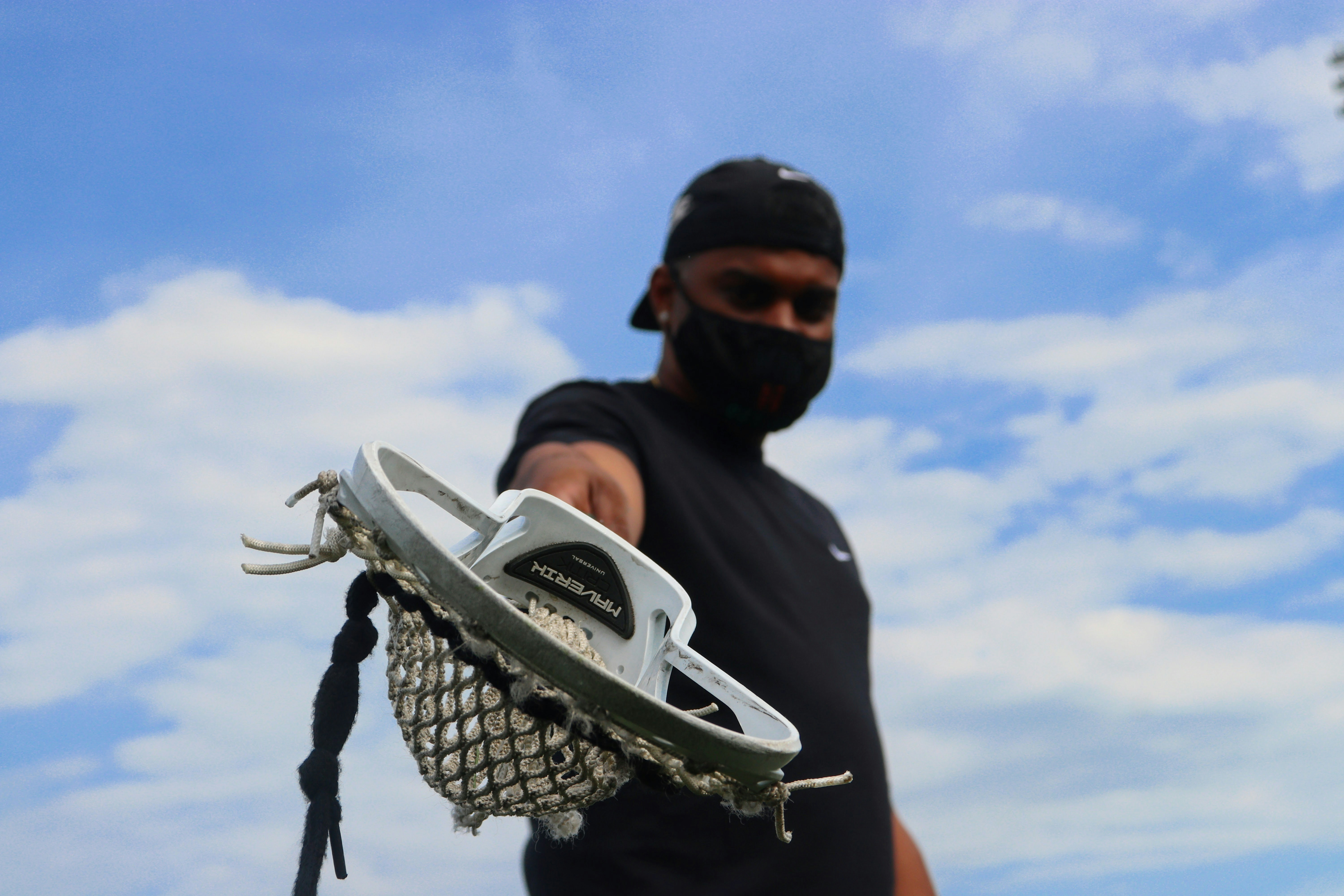A man holding a lacrosse stick at a downward angle to the camera.
